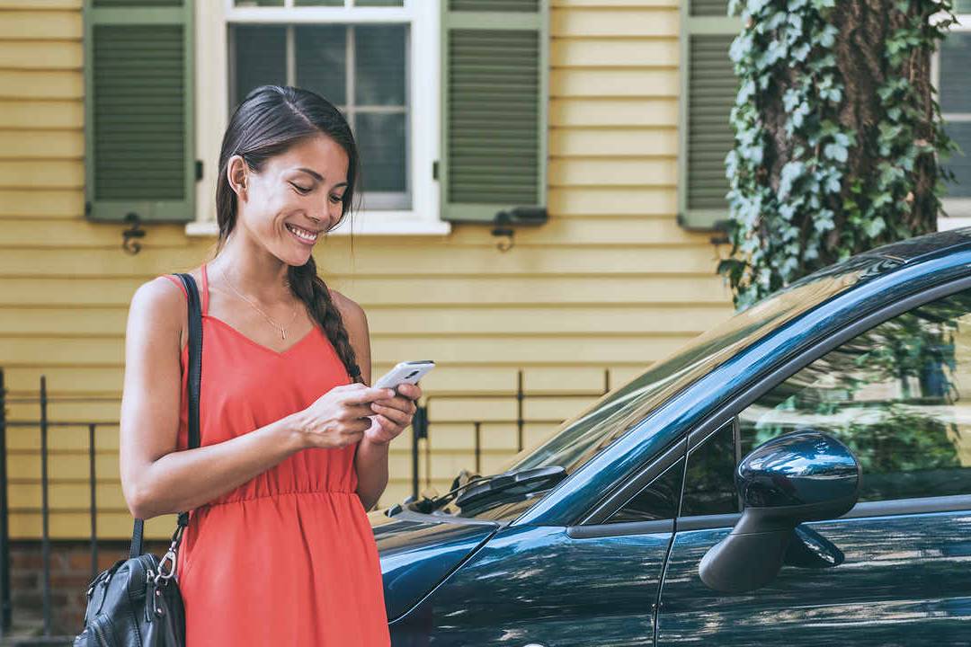 mulher mexe no celular depois de estacionar seu carro na Zona Azul Digital