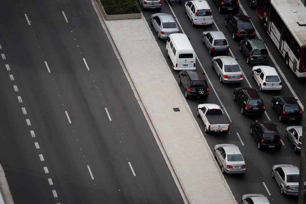 foto de avenida com um lado vazio e com outro lado congestionada por carros