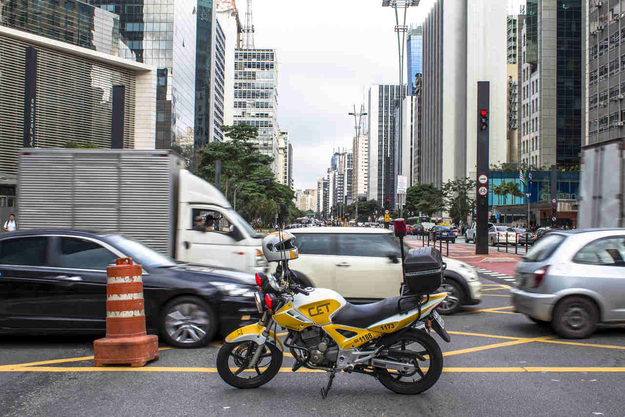 moto de agente de transito da cet parada na avenida paulista enquanto carros passam por ela