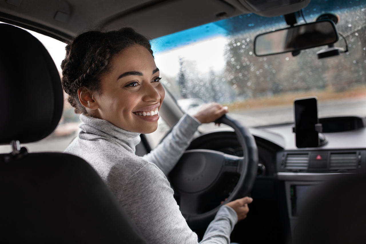 mulher sorrindo dirigindo ao volante